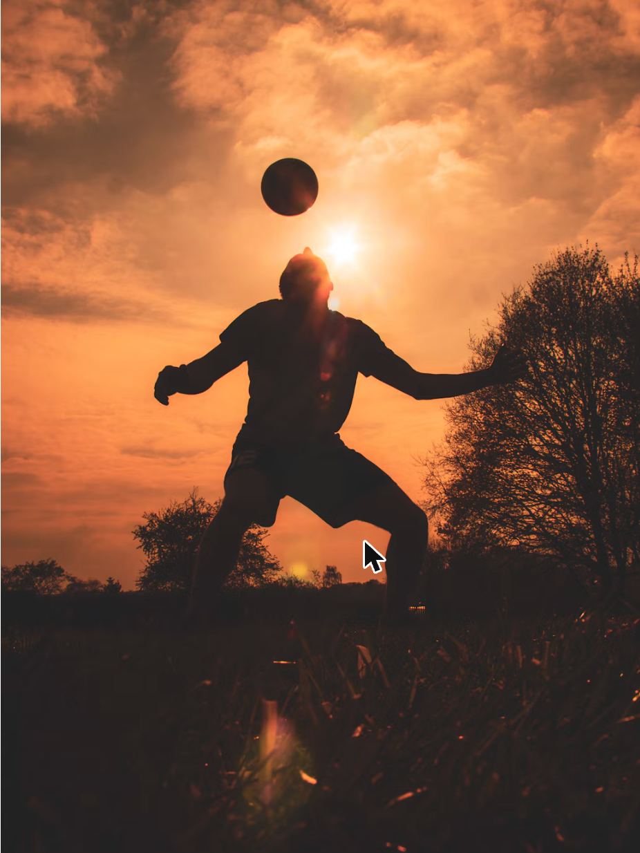 Soccer player heading the ball at sunset